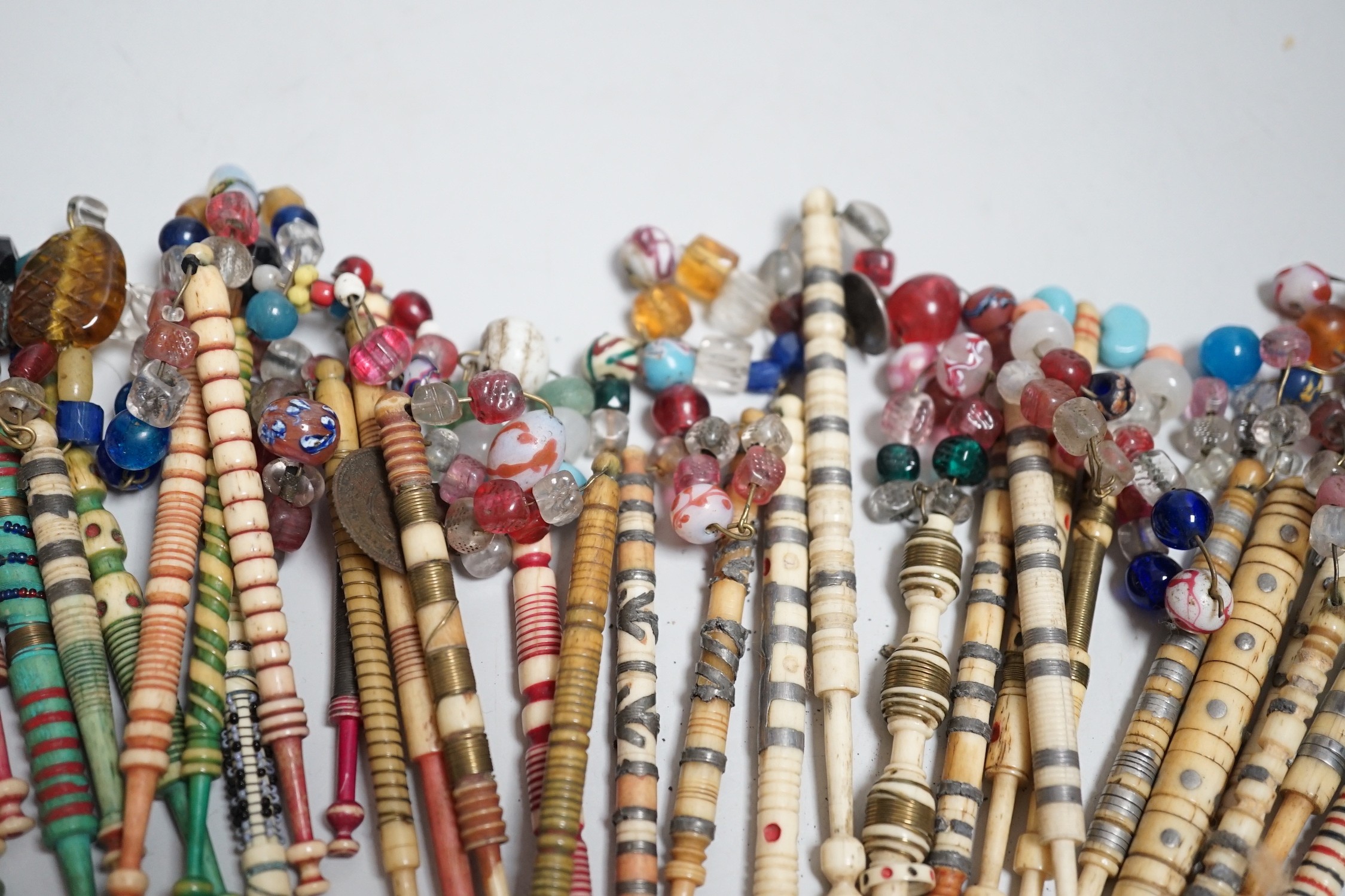 Twenty one 19th century stained and turned bone lace bobbins with glass bead tops and thirteen ornate bone and metal decorated lace bobbins with bead tops (35)